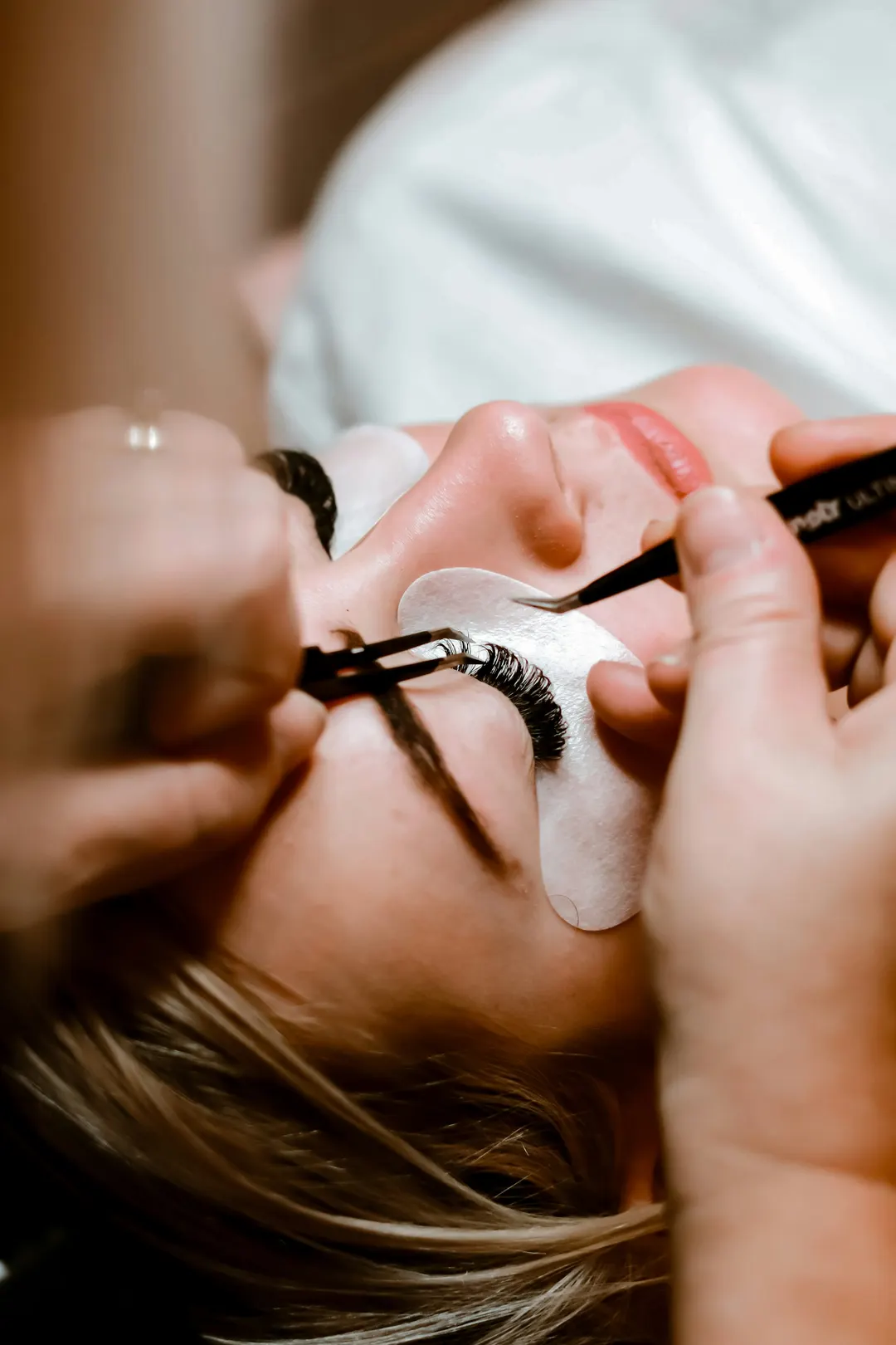 Precyzyjna aplikacja pojedynczych rzęs pęsetami chirurgicznymi w salonie OU Beauty we Wrocławiu